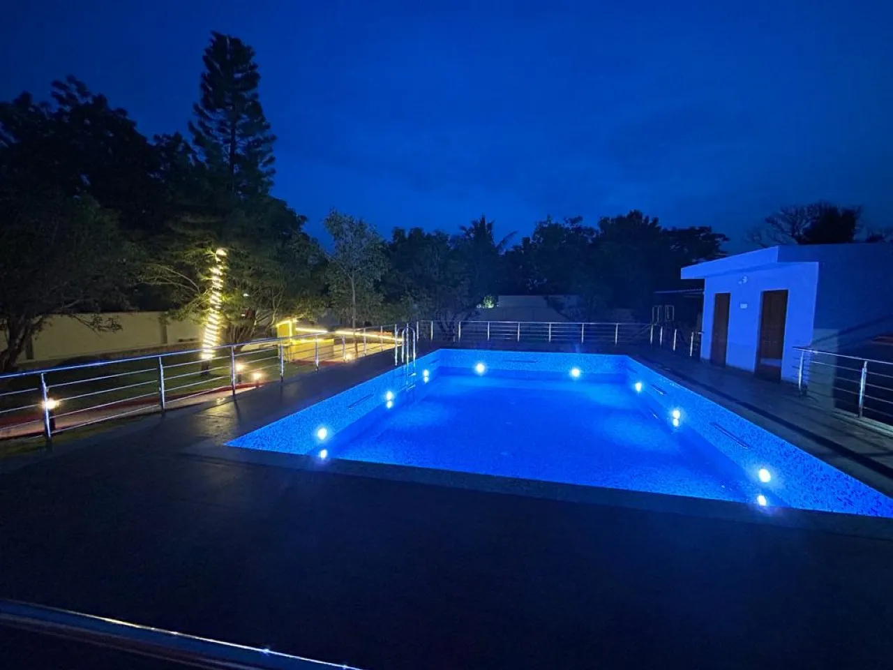 Pool lit up at night at Moon Farm Stay, Kanakamamidi, Moinabad